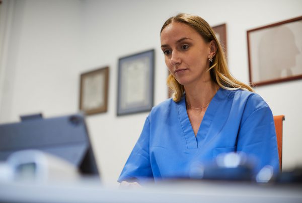 Medical office One nurse typing a report into a digital tablet laptop.