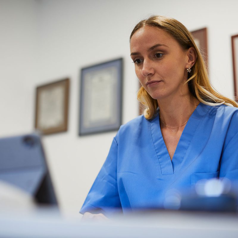 Medical office One nurse typing a report into a digital tablet laptop.