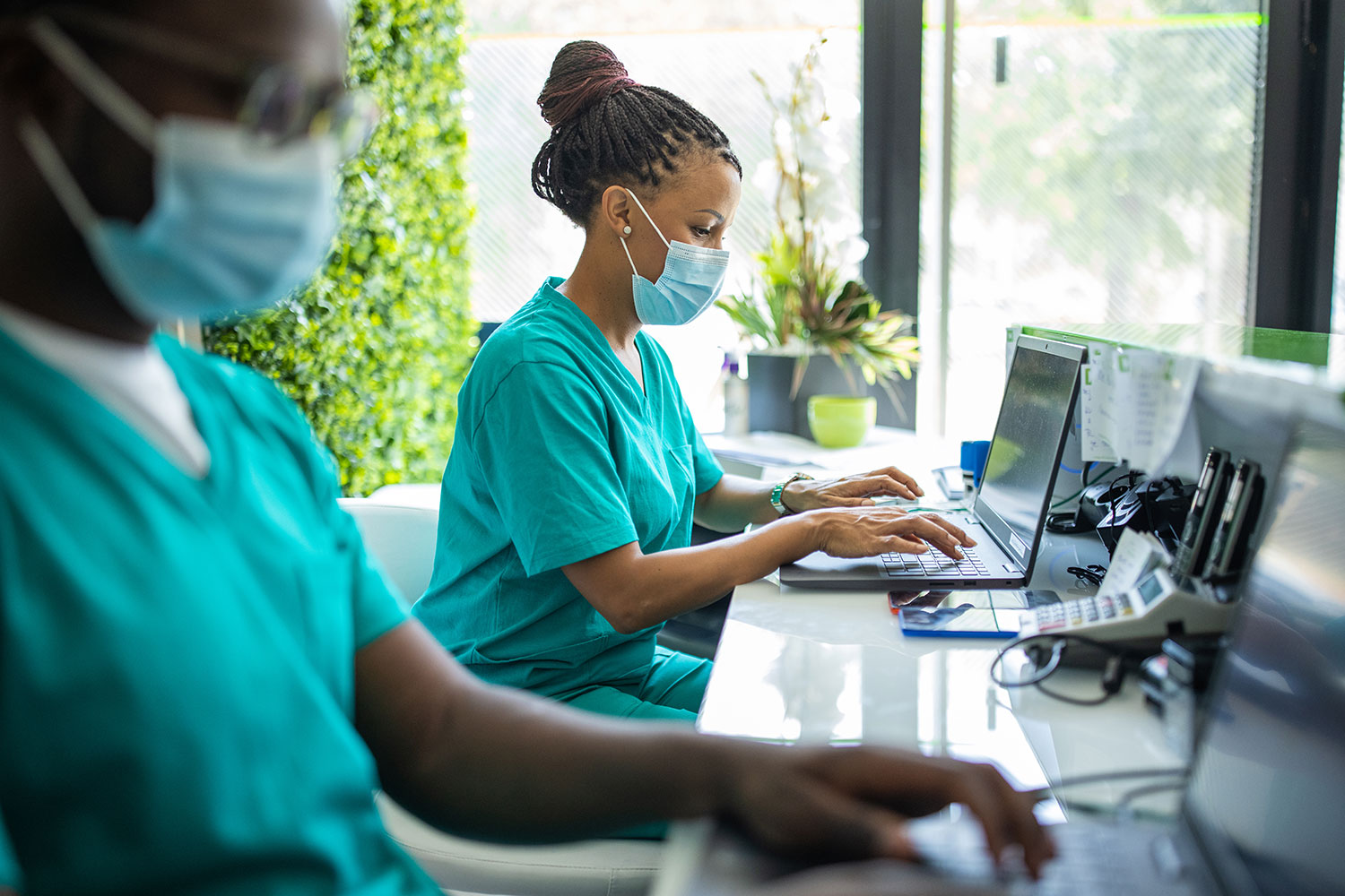 Nurse with protective facemask workin on laptop